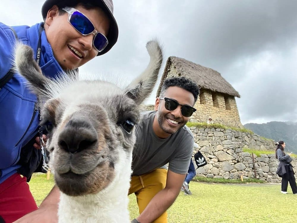 Inca trail Salkantay Tambopata – tourists posing with a llama in front of Machu Picchu ruins