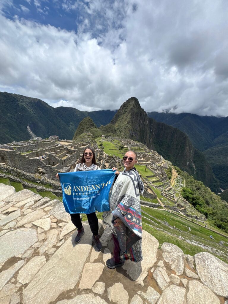 Machu Picchu by train – Andean Top tourists posing with panoramic view of Machu Picchu behind